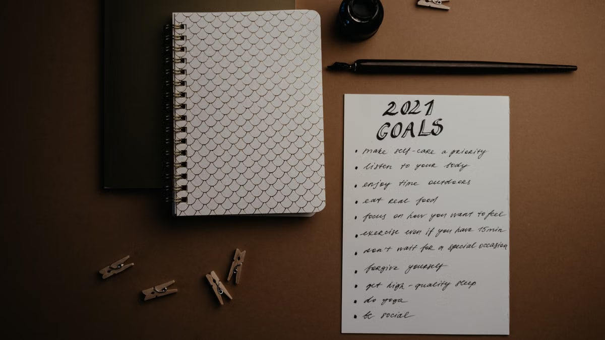 Aesthetic flatlay of notebooks and a 2021 goals list in elegant calligraphy.